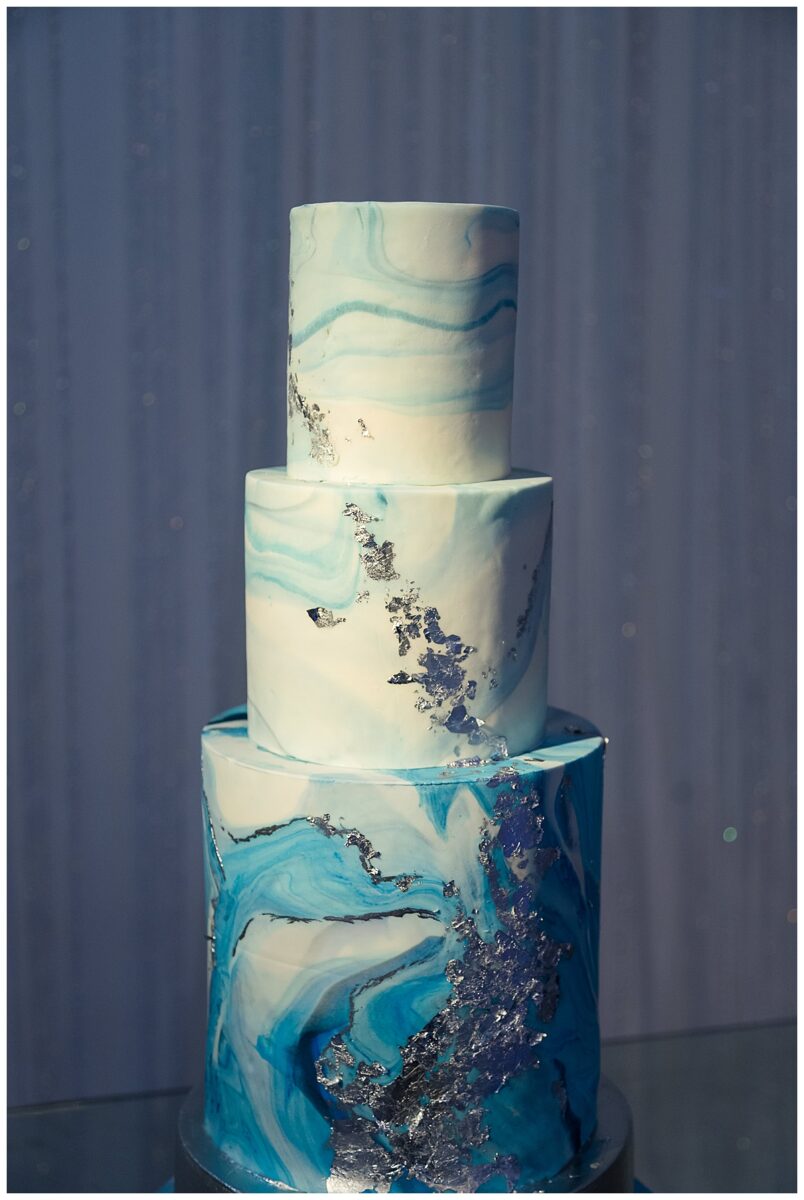 Wedding cake symbolism. A white and blue wedding cake with gold designs at. the Knotting Hill wedding venue in Little Elm, TX.