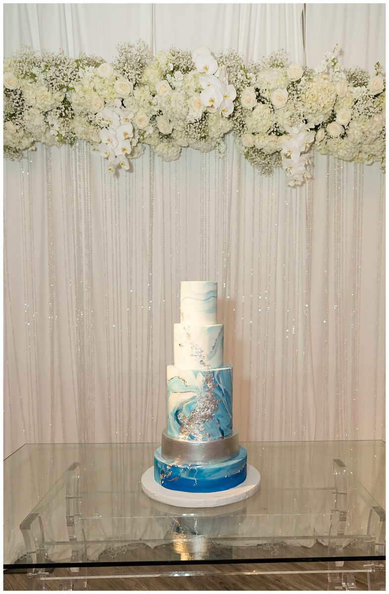 Wedding cake symbolism. A white and blue wedding cake with gold designs at. the Knotting Hill wedding venue in Little Elm, TX.